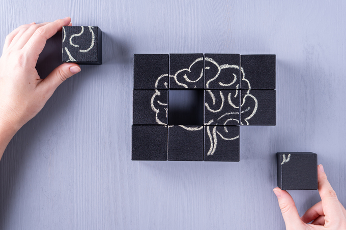 The concept of the human brain. Education, science and medical concept.  Brain drawn in chalk on black cubes.Female hands put in place the last element of the puzzle.