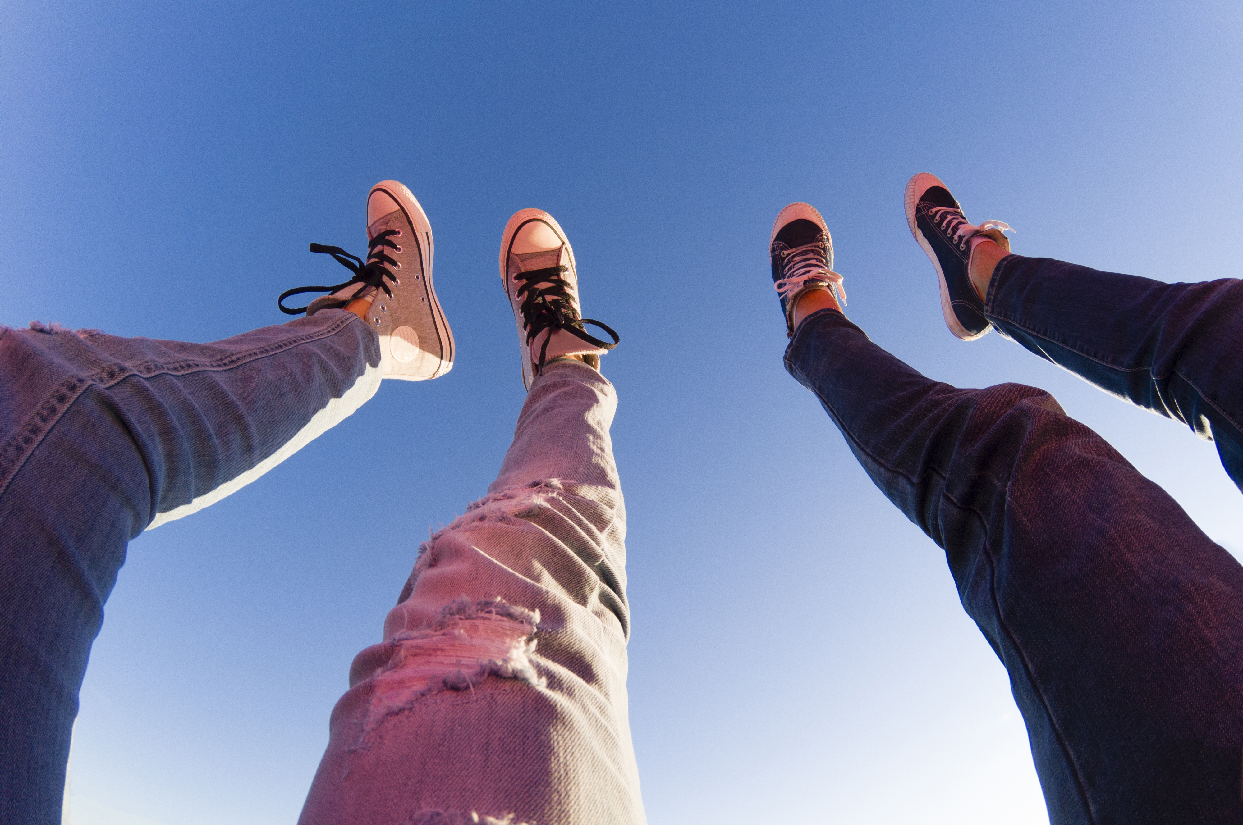 Young couple lifts their legs towards clear blue sky