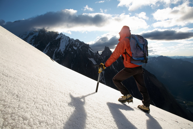 Lone male mountain climber climbing a snowy ridge; Mont Blanc, Europe.