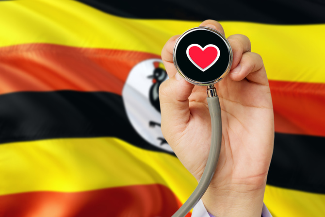 Heil und Heilung / Sezer ÖZGER Doctor holding stethoscope with red love heart. National Uganda flag background. Healthcare system concept, medical theme.