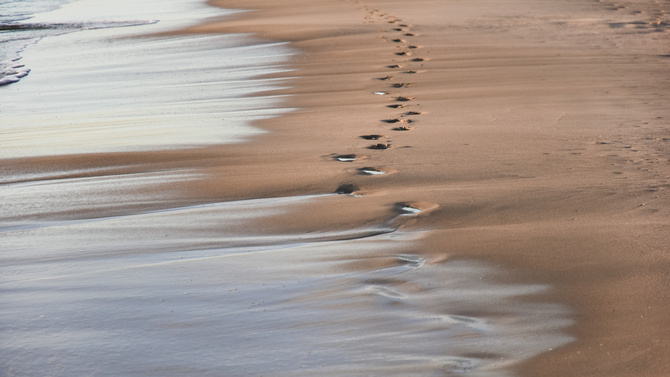 footprints in the sand from the feet of a lost person. no way out of the situation. return to the be