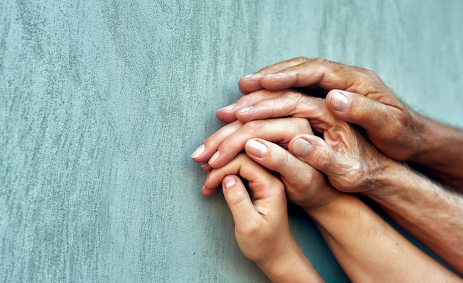 Hands of four generations close-up . Hands of mother, father and grandfather over the child's hand . Family value