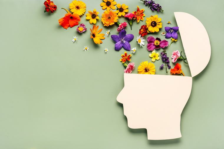 World mental health day concept. Paper human head symbol and flowers on blue background