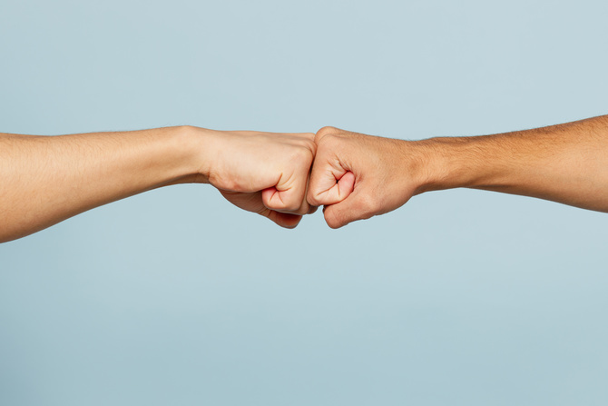 Close up shot of couple two male friends men together hold hands folded fist bump gesture isolated on pastel plain light blue cyan color background studio portrait. Friendship business greet concept