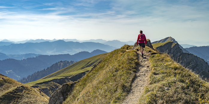 nice senior woman, hiking in fall, autumn  on the ridge of the Nagelfluh chain near Oberstaufen, Allgaeu Area, Bavaria, Germany, Hochgrats summit in the background