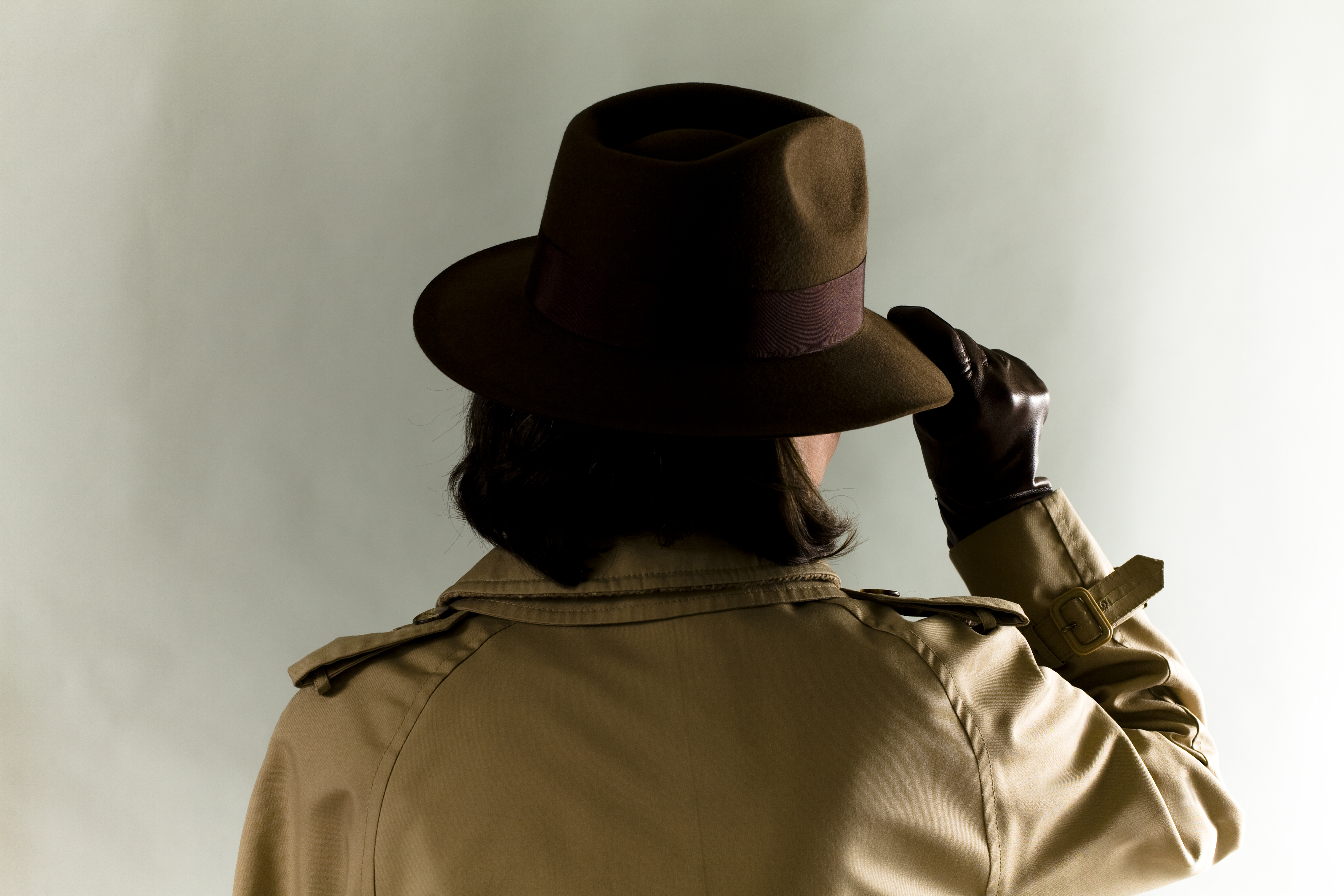 Woman in Indiana Jones style hat, London Fog overcoat and leather gloves.