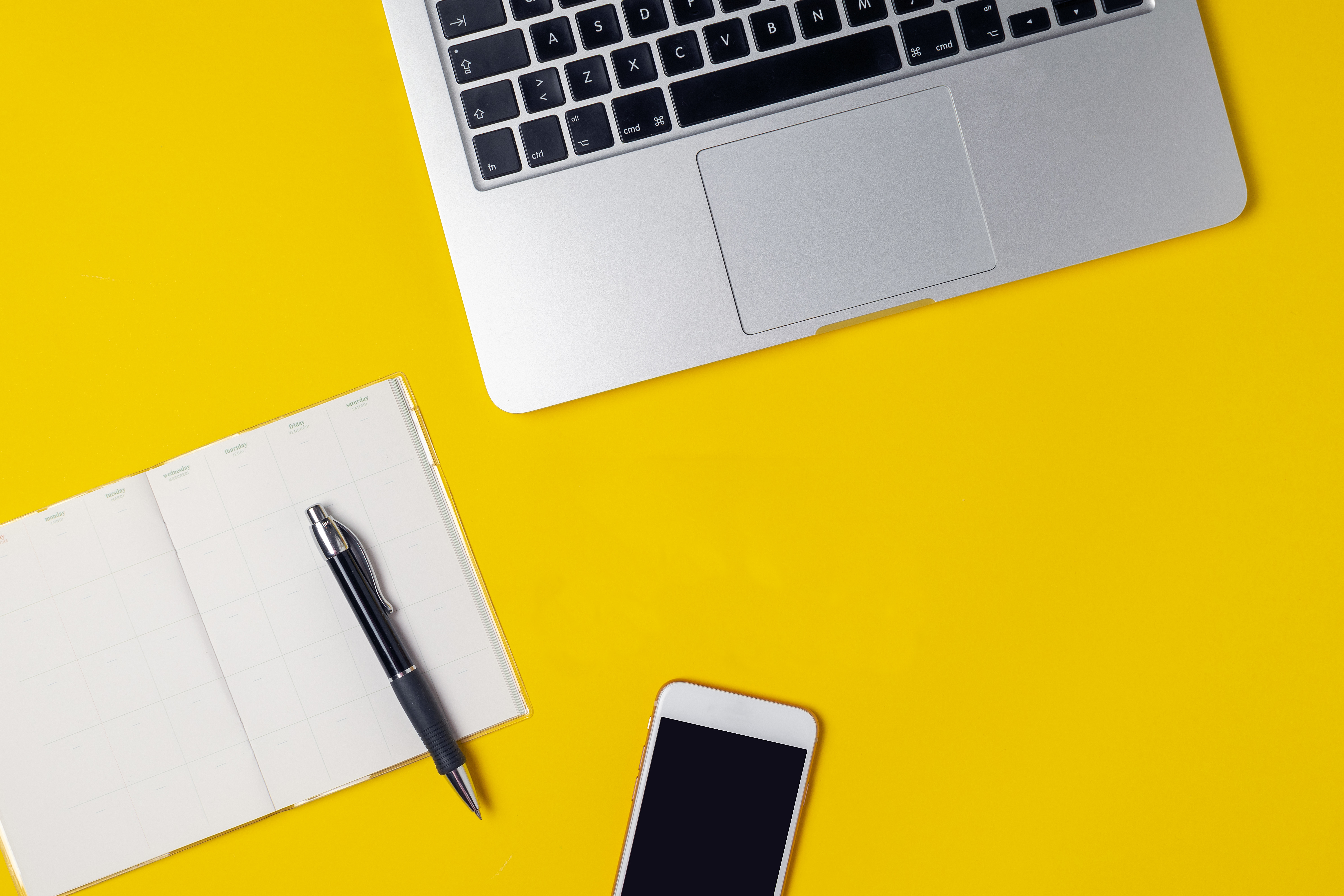 Workspace of freelancer, blogger, journalist - laptop, notepad, pen, coffe cup, smartphone on bright yellow background, top view, flat lay, copy space