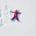 Child girl playing and making a snow angel in the snow. Top flat overhead view