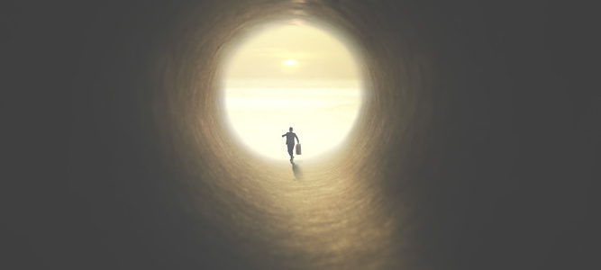 man with suitcase running to the exit of a tunnel illuminated of the sun