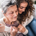 A teenage girl with grandmother at home, hugging. Family and generations concept.