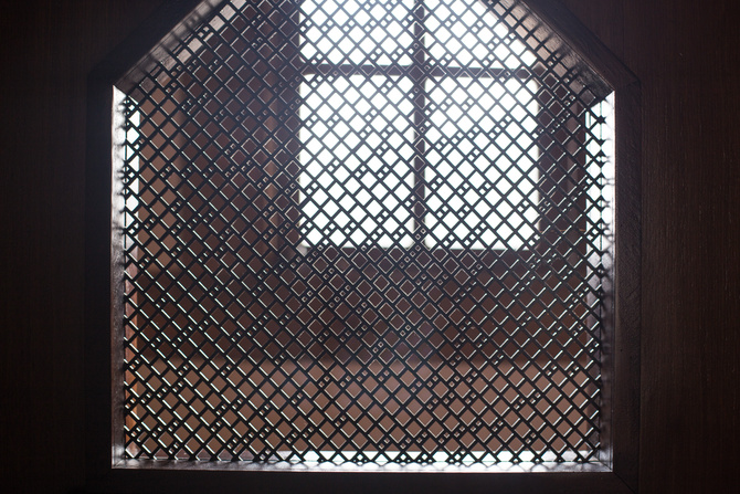 old priest inside the wooden confessional in a Christian church