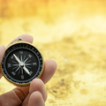 Travel and Business planning concept. Close up of man hand holding vintage compass with world map as background.